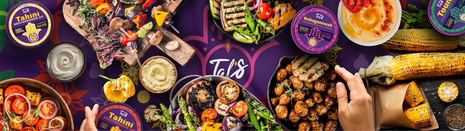 People enjoying various Mediterranean foods and drinks with Tal's Mediterranean dips, set against a backdrop featuring the company’s hamsa logo.