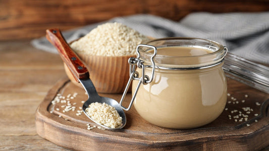 FUN Sesames Tahini Paste | A jar of tahini sauce, a bowl of sesame seeds, and a spoon rest atop the cupboard, ready for culinary adventures.