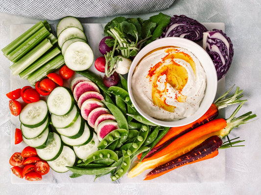 FUN Sesames Tahini Dips | Tahini dips surrounded by assorted vegetables: beans, carrots, cucumbers, cherry tomatoes, purple cabbage, and beets.