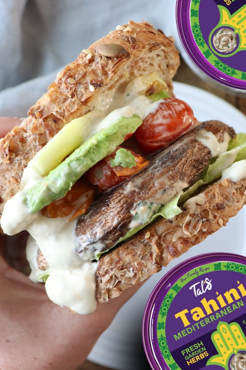 Badass VGN Sandwich on a plate with Tal's Tahini Mediterranean Dip featuring Fresh Garden Herbs flavor.