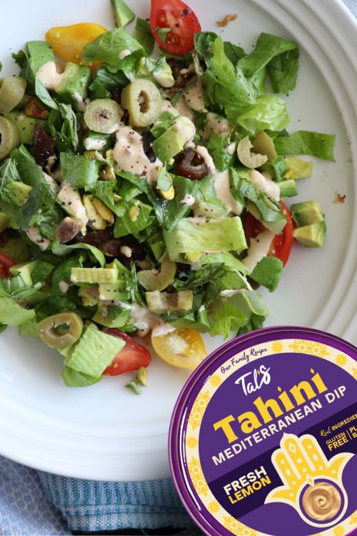 A salad on a plate with Tal's Mediterranean Fresh Lemon Tahini Dip featured at the bottom right.