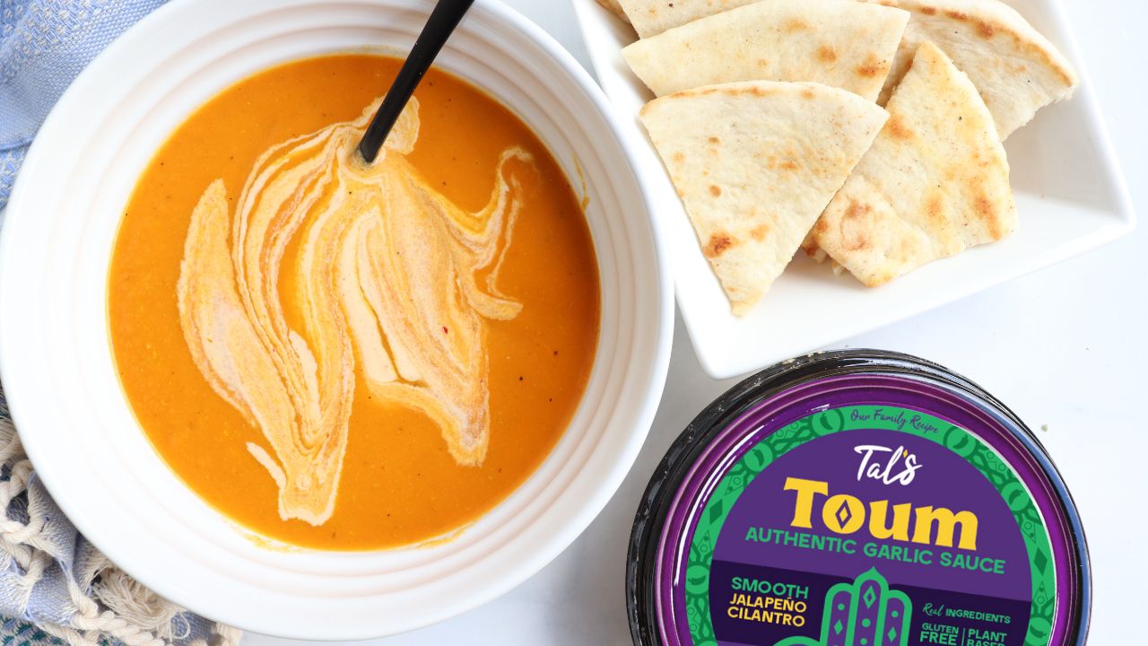 Spicy Kick Carrot Soup on a plate with Tal's Toum Authentic Garlic Sauce Smooth Jalapeno Cilantro featured